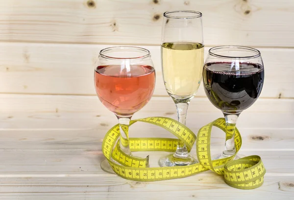 glasses of wine and champagne with measuring tape.Calories in alcohol are extra-fattening