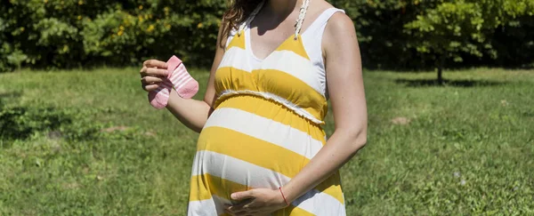 ベビーソックスを持つ妊婦の部分的な眺め — ストック写真
