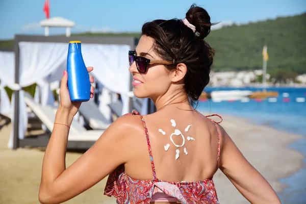 beautiful woman with suntan lotion sunscreen solar cream on the beach