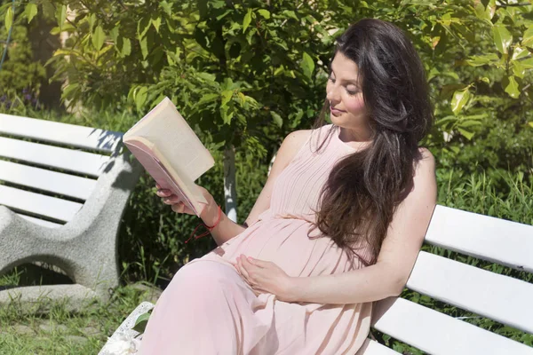 公園のベンチで読んで幸せな妊娠中の女性 — ストック写真