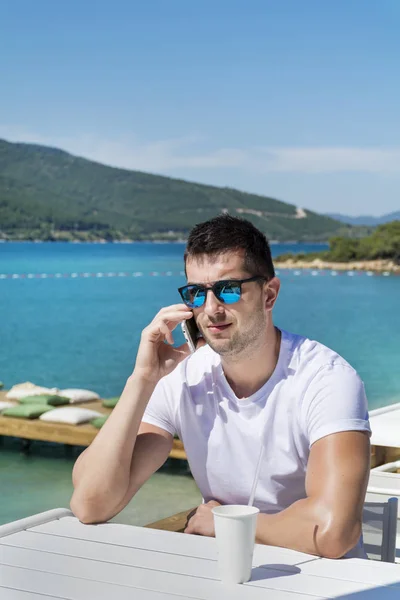 Hombre Gafas Sol Hablando Teléfono Inteligente Cafetería Cerca Del Mar — Foto de Stock