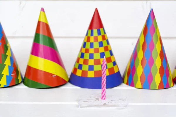 Greeting card for carnival party. Party hat and candles on wooden background