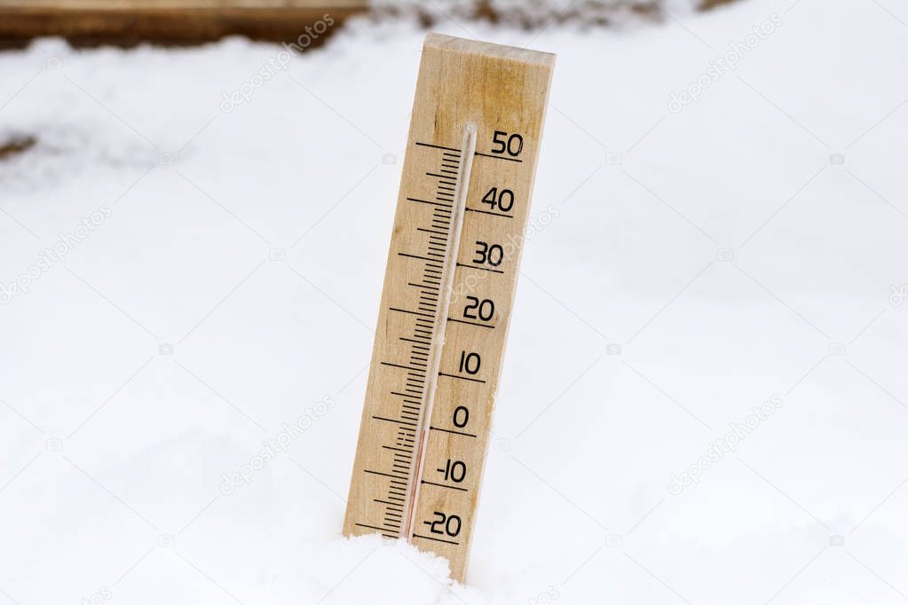 wooden thermometer in the snow