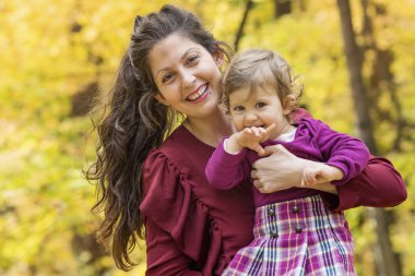 Mutlu anne bebek kızı sonbahar parkta sarılma. Anne ve kızı. Mutlu aile, doğada küçük çocuk ile anne