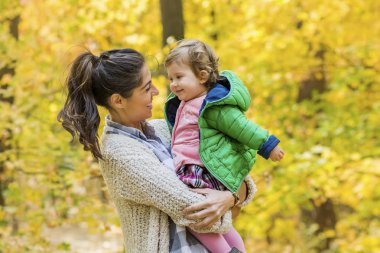 Mutlu anne bebek kızı sonbahar parkta sarılma. Anne ve kızı. Mutlu aile, doğada küçük çocuk ile anne