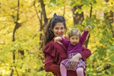 Mutlu anne bebek kızı sonbahar parkta sarılma. Anne ve kızı. Mutlu aile, doğada küçük çocuk ile anne