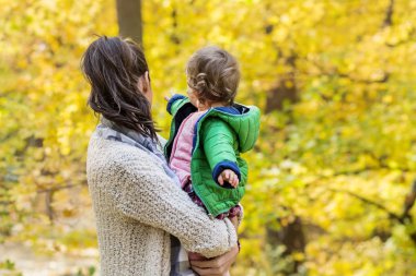 Mutlu anne bebek kızı sonbahar parkta sarılma. Anne ve kızı. Mutlu aile, doğada küçük çocuk ile anne