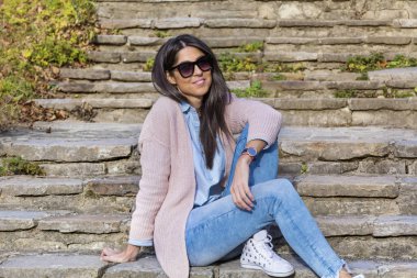 Güzel gülümseyen bir merdivenlerde oturan siyah gözlüklü genç kadın 