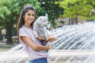 Güzel gülümseyen kadın onu sevimli Havanese köpek sarılma. Evde beslenen hayvan ve sahip açık
