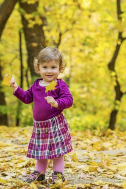 Anne yardım sonbahar parkta yürüyüş için mutlu küçük kız öğrenme