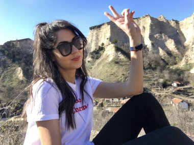 Gülümseyen güzel genç kadın dağ yakınında poz