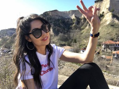 Gülümseyen güzel genç kadın dağ yakınında poz