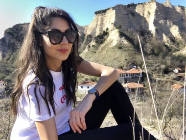 Gülümseyen güzel genç kadın dağ yakınında poz