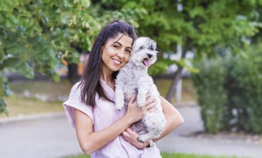 Parkta köpek tutan çekici gülümseyen kadın