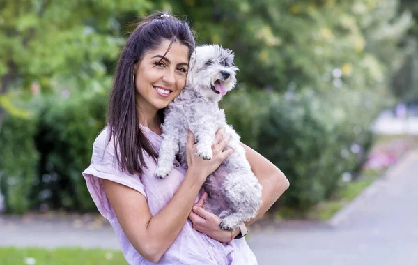 Attractive smiling woman holding dog in park
