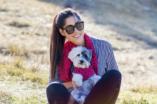 Stylish girl in sunglasses posing with dog outdoors