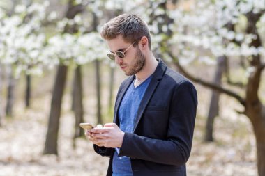 Açık havada akıllı telefon kullanan genç adam. Akıllı Telefona Bakmak