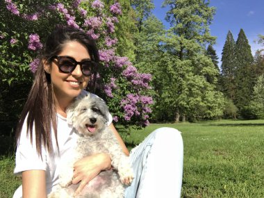 Güzel Gülümseyen Kadın Bir Bahar Bahçesi onu Sevimli Köpek Sarılma . İlkbaharda Evcil Hayvan ve Sahibi Açık