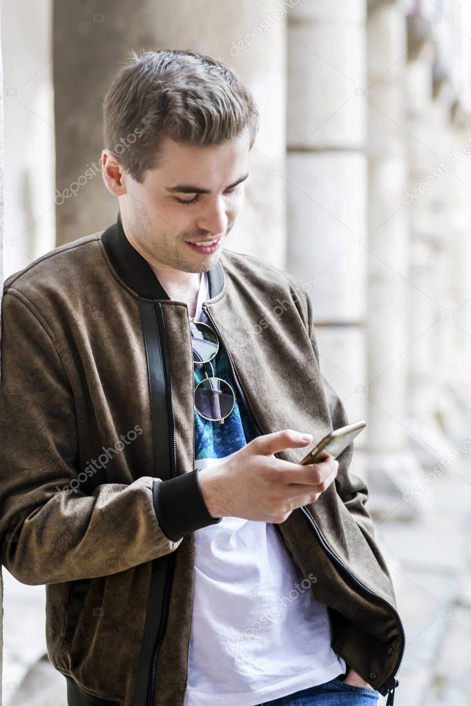 Picture of Young Man Using a Smartphone Outdoor. Looking at Smartphone