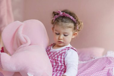 Şirin küçük çocuk evde büyük fil pelüş oyuncağıyla oynuyor. 