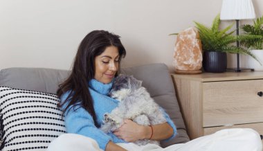 Güzel genç bir kadın, Beyaz kıdemli Havan Köpeğine sarılıyor.