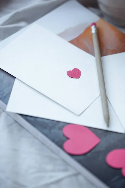 Mockup card with paper hearts. Valentines invitation card with environment. Pencil, magazine, cup. Copy space.