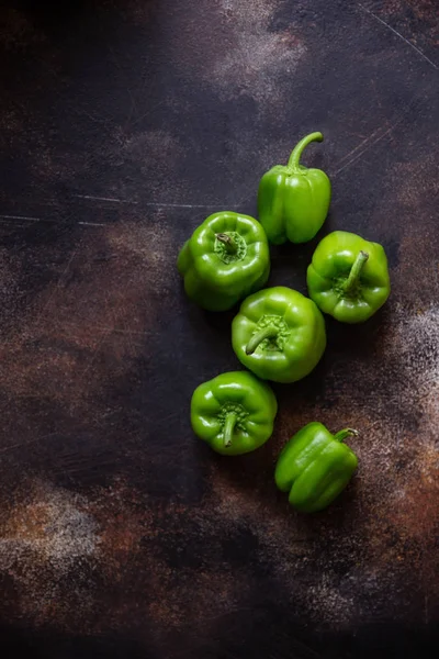 Some green bell peppers on vintage brown table. View from the top. Copy space