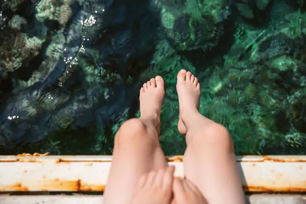 op view of bare feet in the air on the sea. Top view of the feet against the sea or ocean. Summer background. Rest on the ocean, feet on the sea.