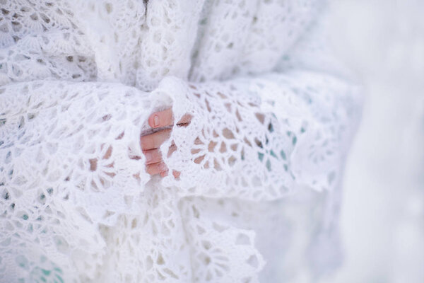 White knitted shawl in winter and girl's hands