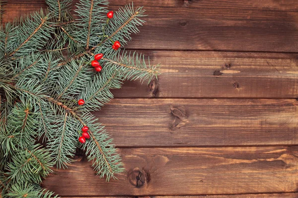 圣诞节冬季绿色树枝与红色新鲜的冬天浆果在木板背景 — 图库照片