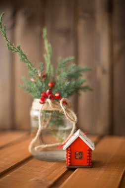 Noel ağacı oyuncak kırmızı ev ve ahşap arka plan üzerinde bir bankada kış meyveleri ile Noel ağacı dalları