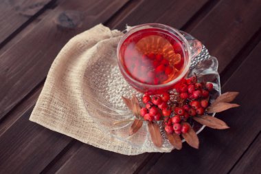 sıcak güzel kokulu kırmızı Rowan çay Rowan branc ile ahşap bir masa üzerinde bir daire ile bir bardak kupa