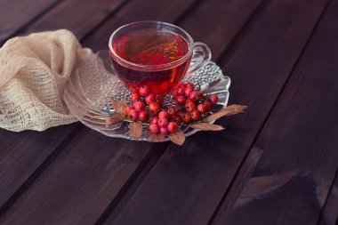 sıcak güzel kokulu kırmızı Rowan çay Rowan branc ile ahşap bir masa üzerinde bir daire ile bir bardak kupa