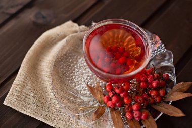 sıcak güzel kokulu kırmızı Rowan çay Rowan branc ile ahşap bir masa üzerinde bir daire ile bir bardak kupa