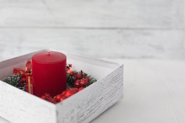 bir beyaz hediye kutusu içinde parlak kırmızı mum beyaz zemin üzerinde bir Noel çelenk ile sarılmış