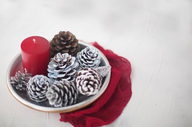 Kış Noel natürmort beyaz zemin üzerine kırmızı mum gümüş koniler ile