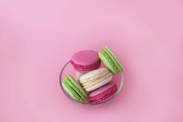 Diversi macaron multicolori in una lastra di vetro su uno schienale rosa — Foto Stock