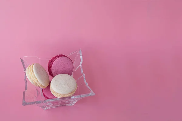 Diversi macaron multicolori in una lastra di vetro su uno schienale rosa — Foto Stock