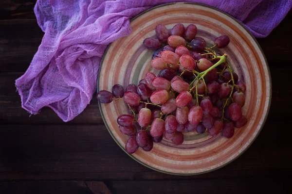 Виноград на тарілці на дерев'яному фоні — стокове фото
