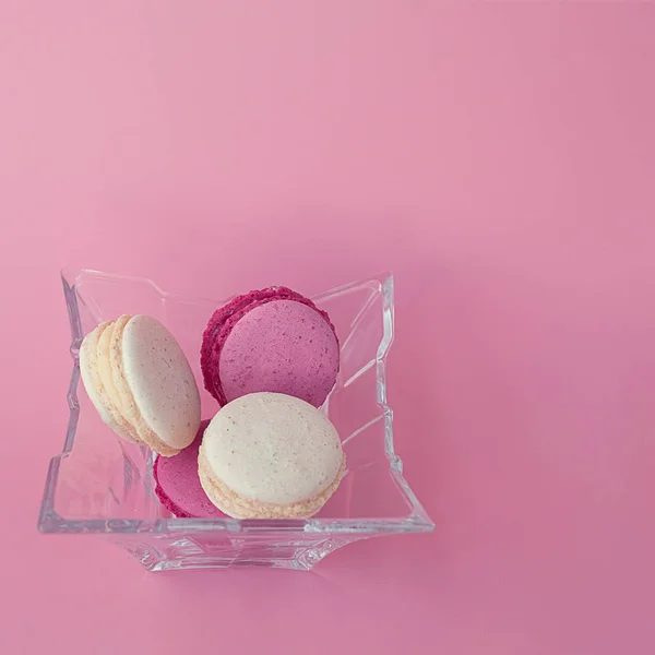Diversi macaron multicolori in una lastra di vetro su un quadrato rosa — Foto Stock
