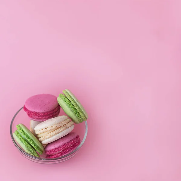 Diversi macaron multicolori in una lastra di vetro su un quadrato rosa — Foto Stock