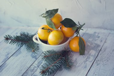 ahşap bir bac üzerinde beyaz bir tabakta yaprakları ile mandalina mandalina