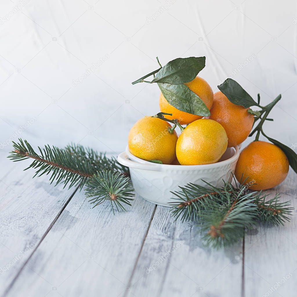 tangerines mandarin with leaves in a white plate on a wooden bac