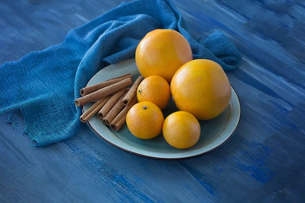 Laranjas e tangerinas com canela em uma placa azul e wa azul — Fotografia de Stock