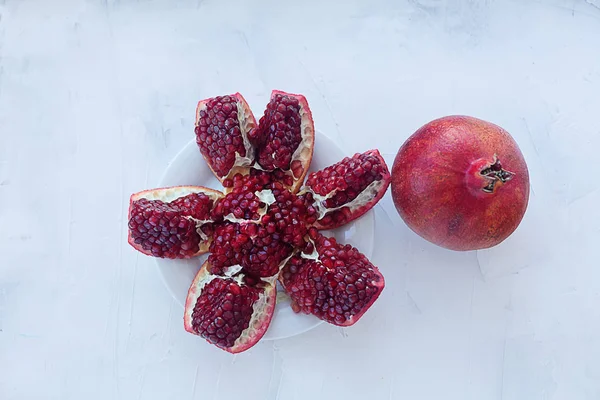 Fruta de romã fatiada em um fundo de textura branca . — Fotografia de Stock