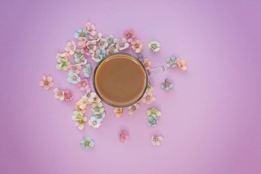 Pembe arka planda çiçekli bir fincan kahve. Model ve projeniz için minimalist bir konsept. Düzen, düzlük, kopyalama alanı, üst görünüm. Seçici odak.
