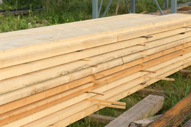 Yeşil çimlerin üzerinde ahşap inşaat kirişleri. İnşa ediliyor.