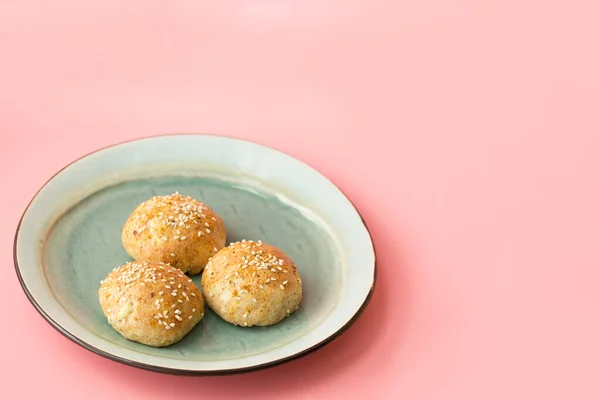 Fresh buns with sesame seeds on a blue plate on a pink horizontal background. Selective focus. Layout, copy space.