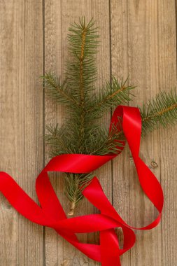 Noel kompozisyonu. Noel ağacı dalı ve ahşap bir arka planda kırmızı kurdele. Seçici odaklanma. Düzen, düz yatış, kopyalama alanı, üst görünüm.