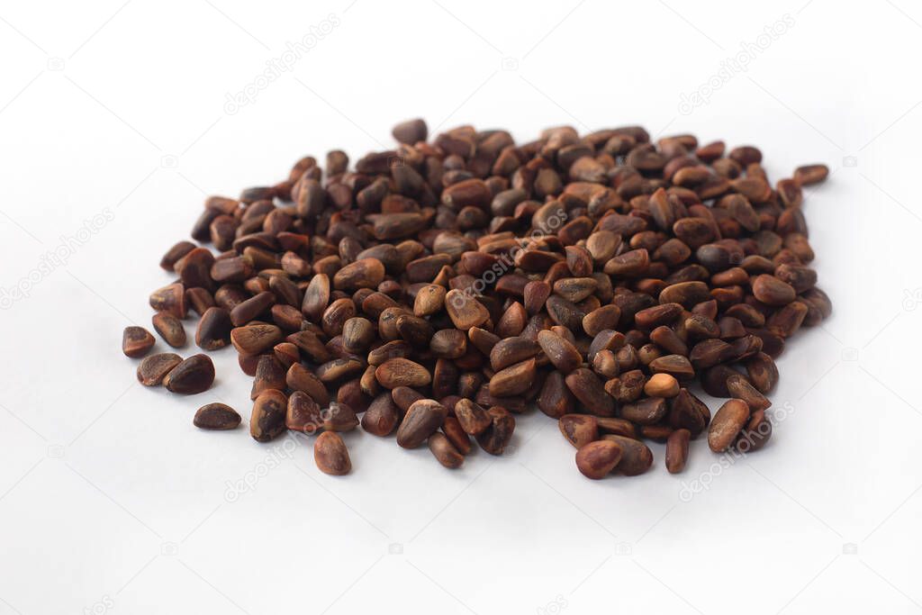 Heap of unshelled pine nuts on a white background. A useful product for health.